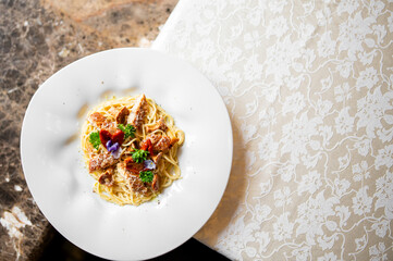 Plate of spaghetti with grilled chicken, garnished with herbs and edible flowers on a floral...