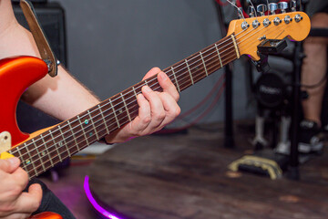 Guitarist playing on the neck of a red electric guitar	
