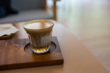 A glass of dirty coffee served on wood tray