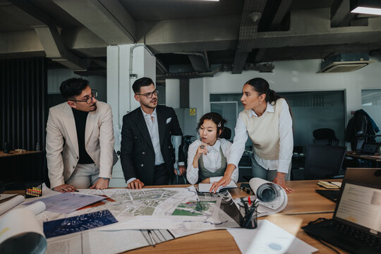 A group of four people, including a project leader with crutches, actively discusses project plans with charts and paperwork in a modern office setting.
