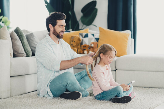 Father bonding with daughter while braiding her hair at home