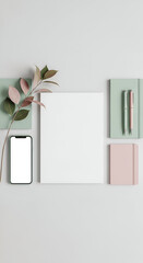 Flat lay composition featuring a blank canvas, smartphone with a white screen, notebooks, pen, and decorative branch on a light grey background.