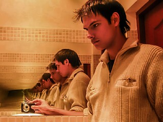 a guy in a knitted sweater is reflected multiple times in the mirror	

