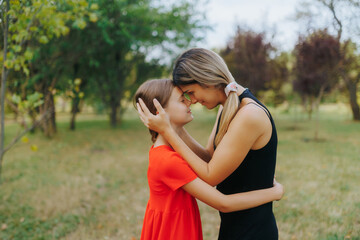 Mother and daughter share sweet hug in sunny park setting