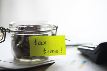 Jar of Coins with Tax Time Note, Calculator, and Paperwork - Financial Planning and Tax Season Concept