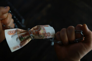 Struggle for Money: Hands Pulling Chain Wrapped Around Russian Rubles in Dark Background