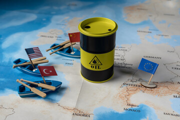 An oil barrel labeled “OIL” on a map, with miniature boats flying international flags (the US, Turkey, China, and the European Union), depicting the global energy market and competition for resources