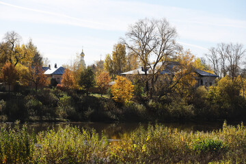 Autumn Landscape with River, Trees, and Homes under Clear Blue Sky