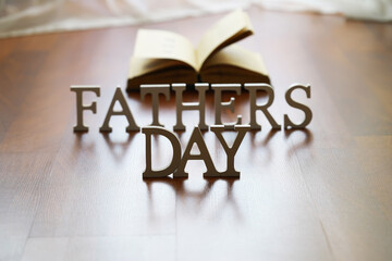 Father's Day Concept with Wooden Lettering and Open Book on Wooden Floor