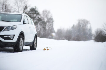 White SUV on a Snowy Road in Winter with Sled in Background in Serene Countryside
