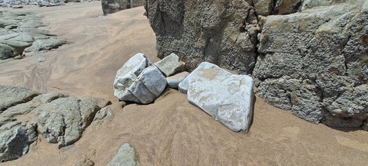 Weathered rocks resting on sandy beach