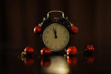 Vintage Alarm Clock Decorated with Red Christmas Ornaments on a Dark Background