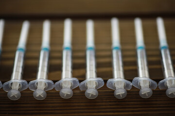 Row of Medical Syringes for Vaccination, Healthcare, or Medical Procedures on a Wooden Surface