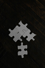 White Puzzle Pieces on Dark Wooden Background - Simple, Minimalist, Conceptual Stock Photo