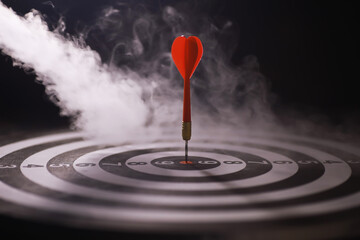 Red Dart Hitting Bullseye on Smokey Dartboard - Precision and Accuracy Concept