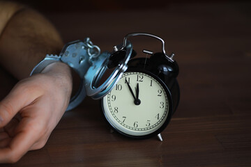 Handcuffed Person with Alarm Clock Symbolizing Time Constraints and Restriction