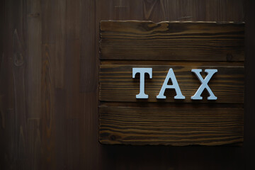 Wooden Sign with 'TAX' Letters on Dark Wood Background - Financial Concept Image