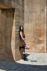 Latin woman, young and pretty brunette with tattoos on her arms and legs, wearing a brown dress and...