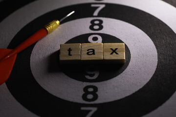 Tax Concept with Wooden Blocks on Dartboard, Red Dart Hitting the Target, Symbolizing Financial Accuracy