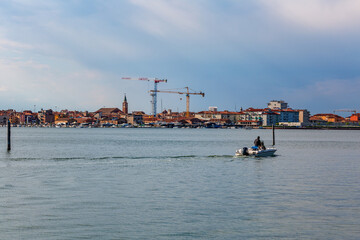 Quiet everyday life on the lagoon of Chioggia, Italy. Construction of a new high-rise building in the distance