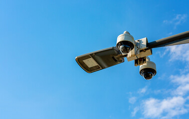 Surveillance camera system mounted on a pole against a clear blue sky, showcasing advanced technology for security monitoring and public safety in urban environments