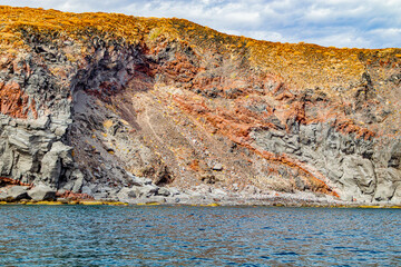 Eroded slope on Mexican coastline, volcanic lava rock formations, yellowish-brown plants on top, Coronado Island Protected Area, Loreto Bay National Marine Park in Baja California Sur, Mexico