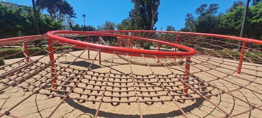 Red rope climbing net in a sunny outdoor playground
