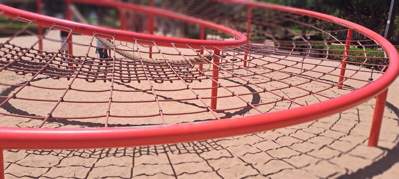 Curved red playground climbing structure with netting