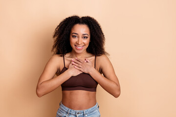 Happy young woman in casual style expressing gratitude while standing against a beige background