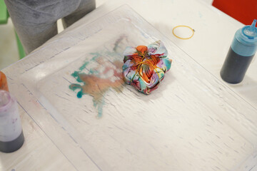 Close-up of a child applying blue dye to a tied fabric in a tie-dye project. Fun and creative...