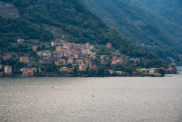 A compact cluster of colorful buildings extending up a hillside from the edge of a calm lake