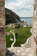 A scenic view of green park, road, and Danube River through the stone window of Golubac Fortress in...