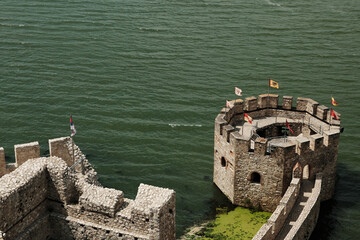 Close-up top view of a round stone tower with flags at Golubac Fortress on the Danube River, Serbia...