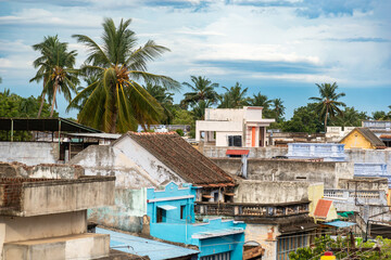 View of colorful rooftops in Kallidaikurichi, Tamil Nadu adorned with palm trees under a cloudy...
