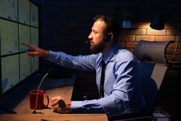 Security guard monitoring CCTV cameras in office at night