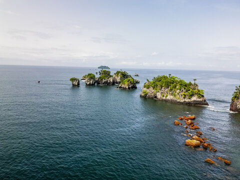 Aerial view of verdant isles rising from the deep blue, meeting the sky with a serene horizon, framed by rugged rocks and gentle waves, Limbe, Southwest Region, Cameroon.