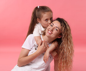 Family portrait of happy mother and her daughter on pink background