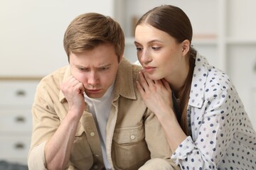 Young woman apologizing to her offended boyfriend at home