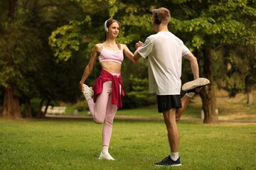 Couple in headphones doing morning exercise in park