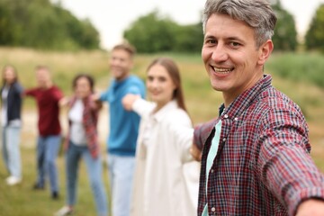 Team building. Group of happy people holding hands outdoors, selective focus