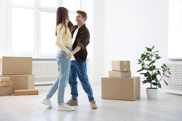 Happy young couple dancing and cardboard boxes at home, low angle view. Moving day