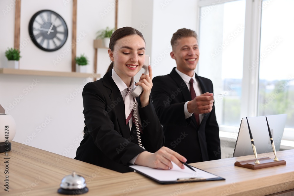Poster smiling receptionists working at reception desk in hotel