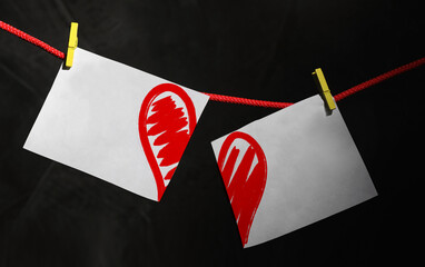 Betrayal. Cut in halves paper with red heart on rope against black background