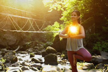 Woman meditating in Tree pose in mountains. Glowing bubble representing chakra