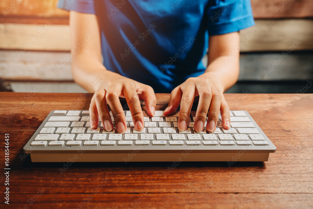 Poster hands typing on keyboard with wooden table background