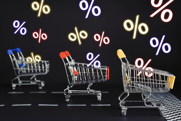 Percent signs flying out of shopping carts racing on black background. Hot sale, special offer