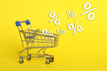 Hot sale, special offer. Percent signs flying out of shopping cart against yellow background