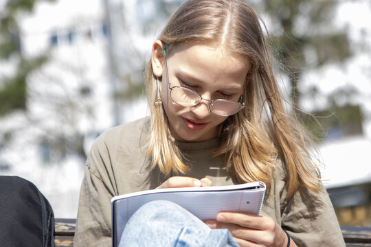 Young student focused on writing outdoors