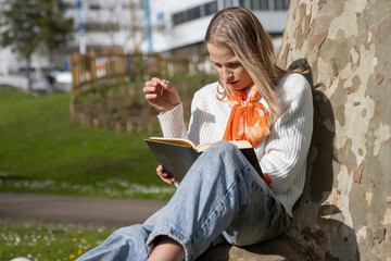 Young woman reading a book outdoors in spring