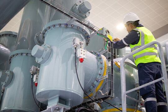 Technician performs maintenance on large insulated gas switchgear in substation ensuring safety and reliability in electrical power distribution systems